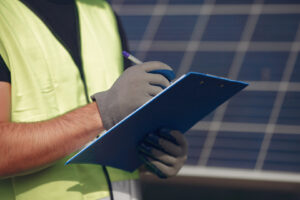 Engineer in a white helmet. Man near solar panel. Worker with a folder.